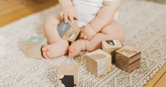 Baby sitzt inmitten von Bausteinen.