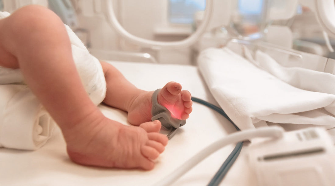 Frühgeborenes im Brutkasten, Detailaufnahme Fuß mit Monitorkabel
