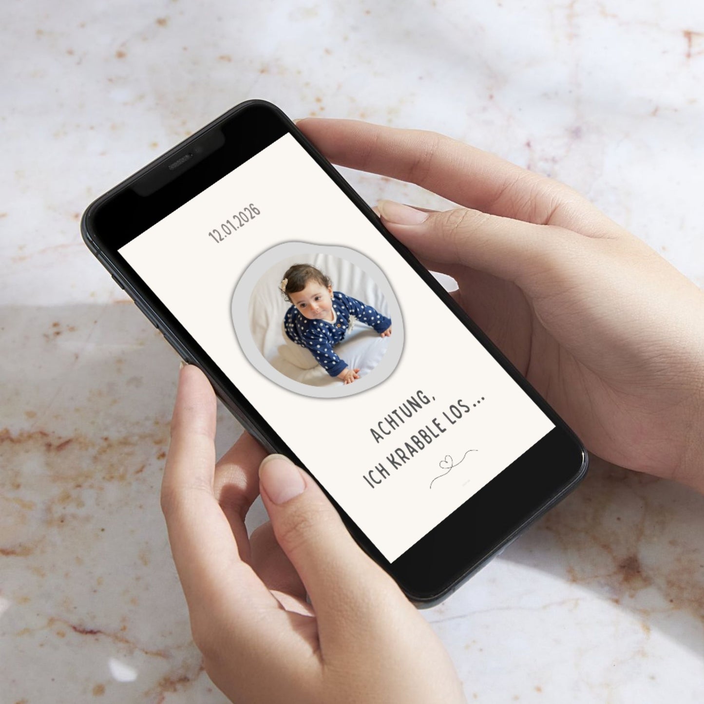 Eine Person hält ein Smartphone in der Hand, auf dem eine ausgefüllte digitale Baby-Meilensteinkarte mit einem Foto eines krabbelnden Babys und dem Text "Achtung, ich krabble los..." zu sehen ist.